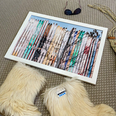Pair of fluffy slippers with a framed artwork of feathers on a textured surface.