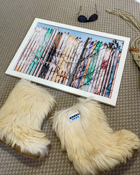 Furry slippers next to a framed artwork of feathers on a textured surface