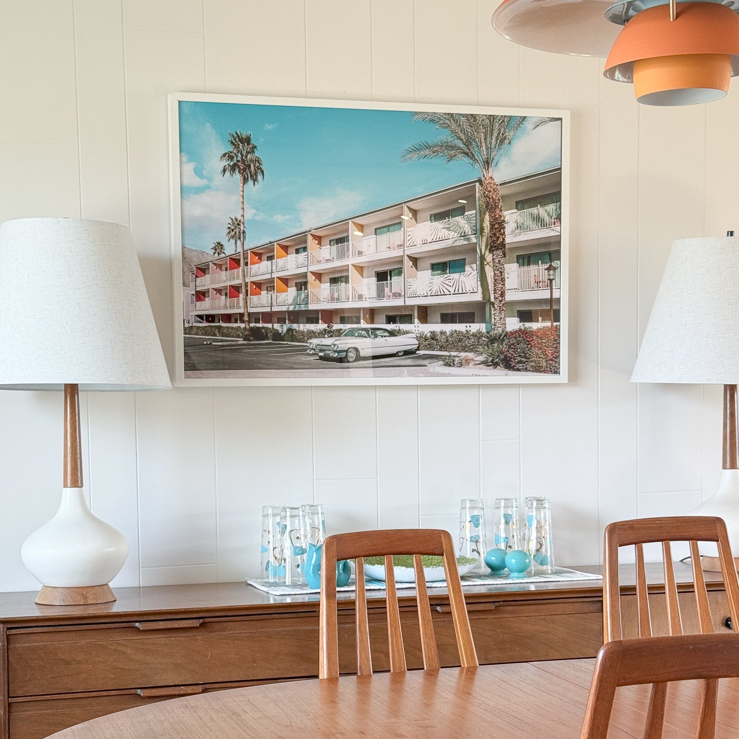 Dining room with wooden table and chairs, framed artwork on the wall, and lamps.