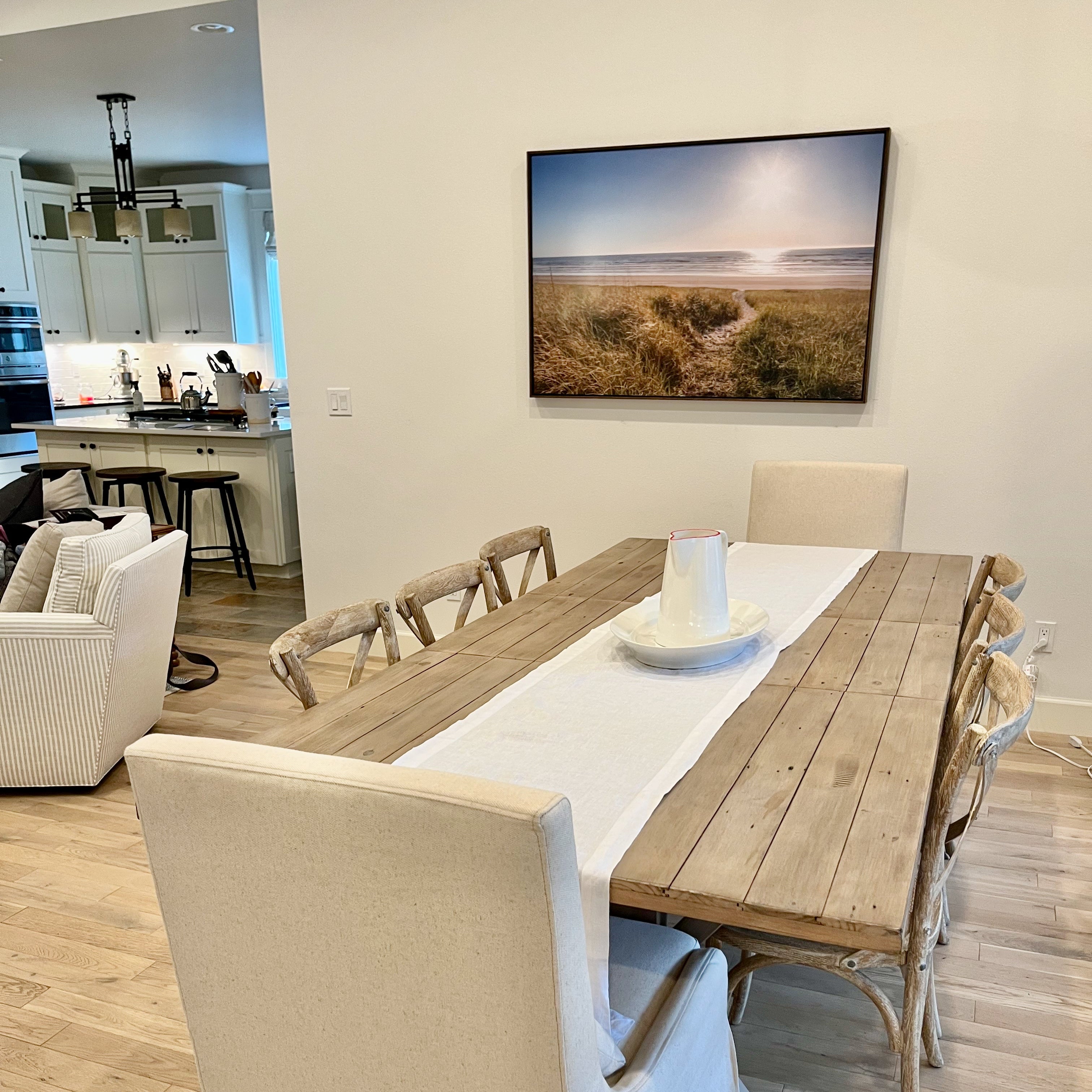 Dining room with wooden table and chairs, kitchen in the background