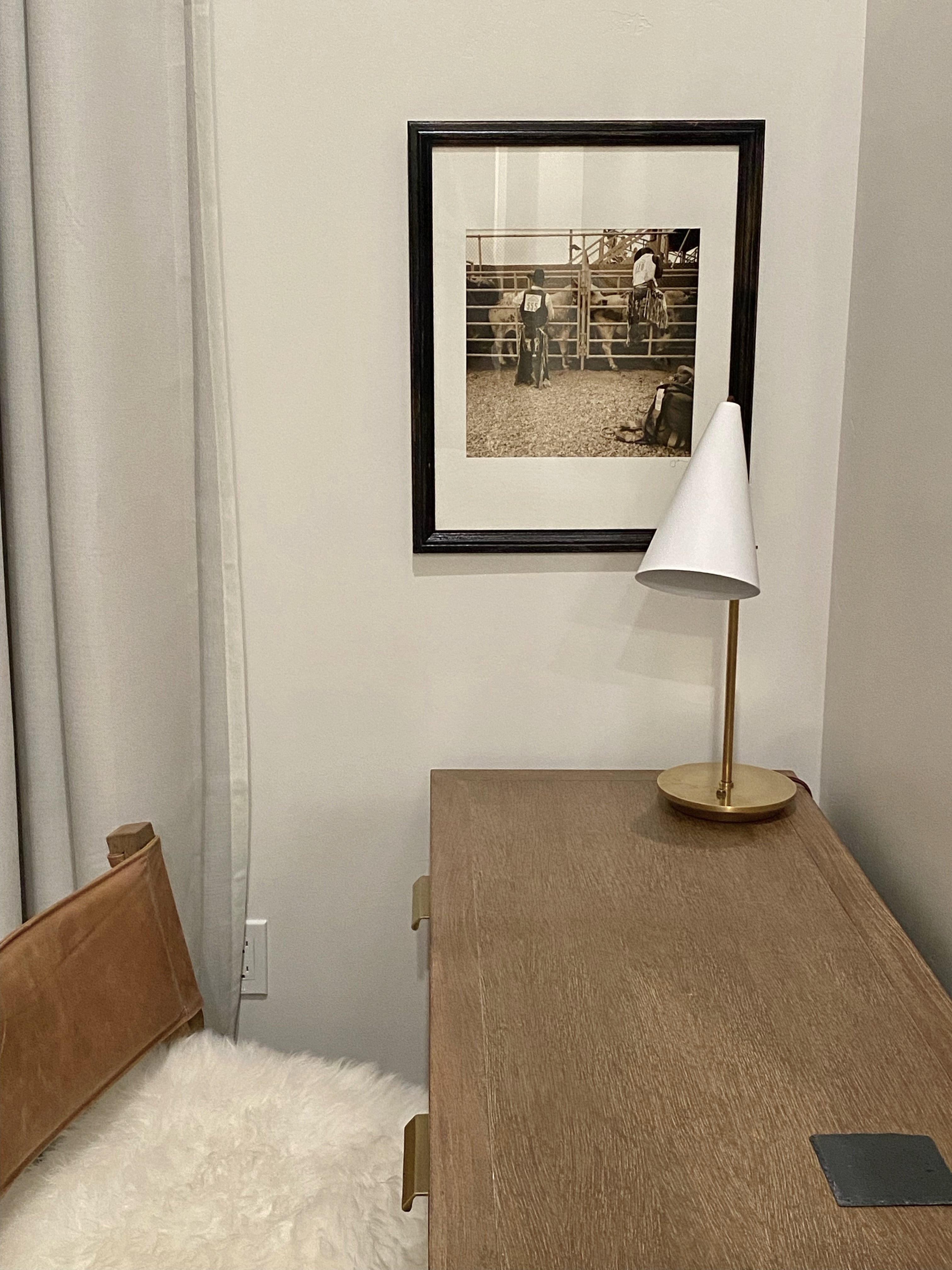 Room interior with a desk, lamp, and framed picture on the wall.