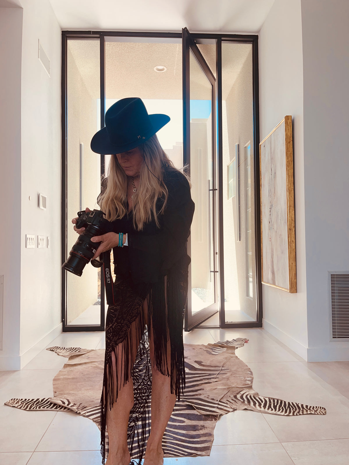 Person holding a camera in a modern interior setting with large glass doors.