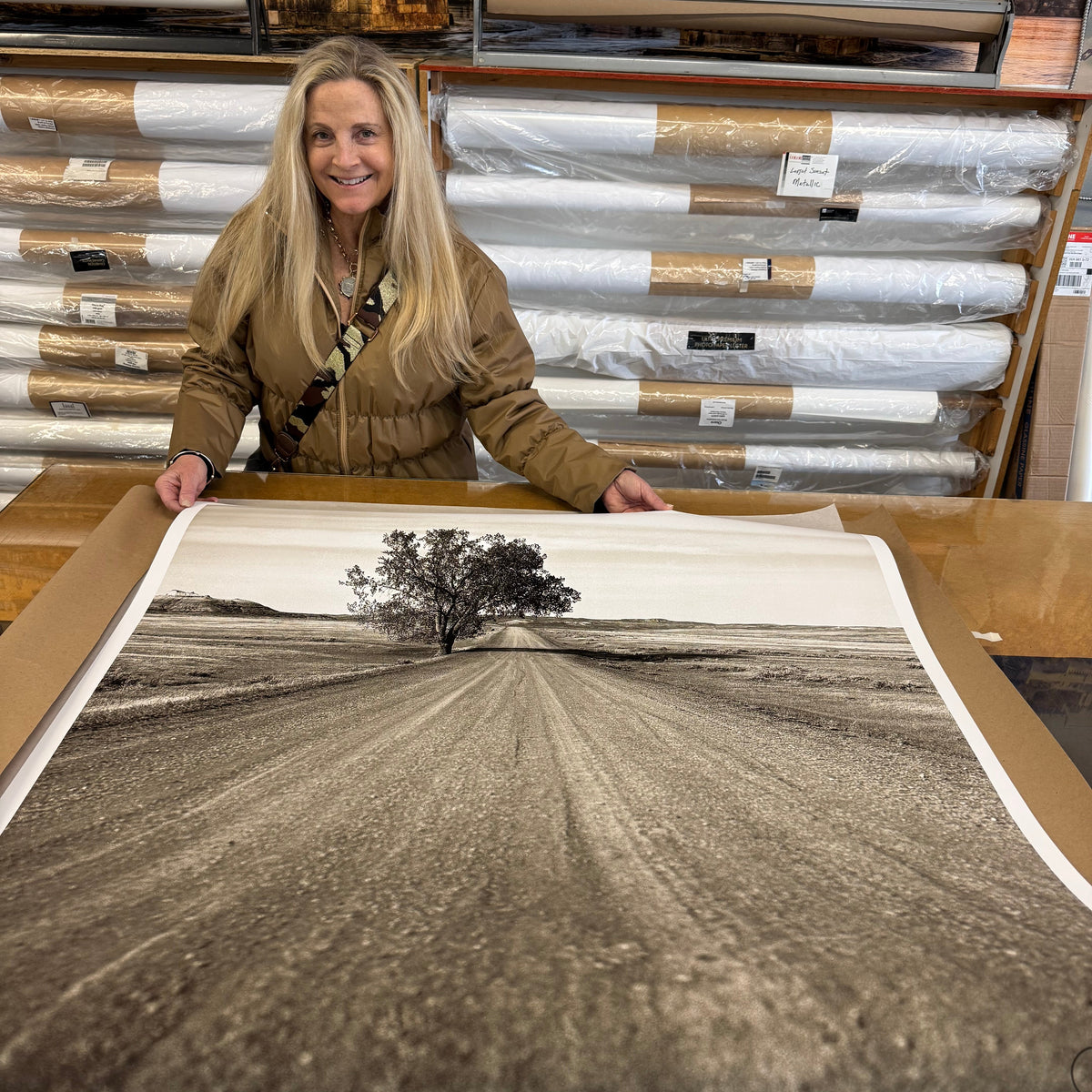 Woman looking at large rolled-up artwork in a gallery.