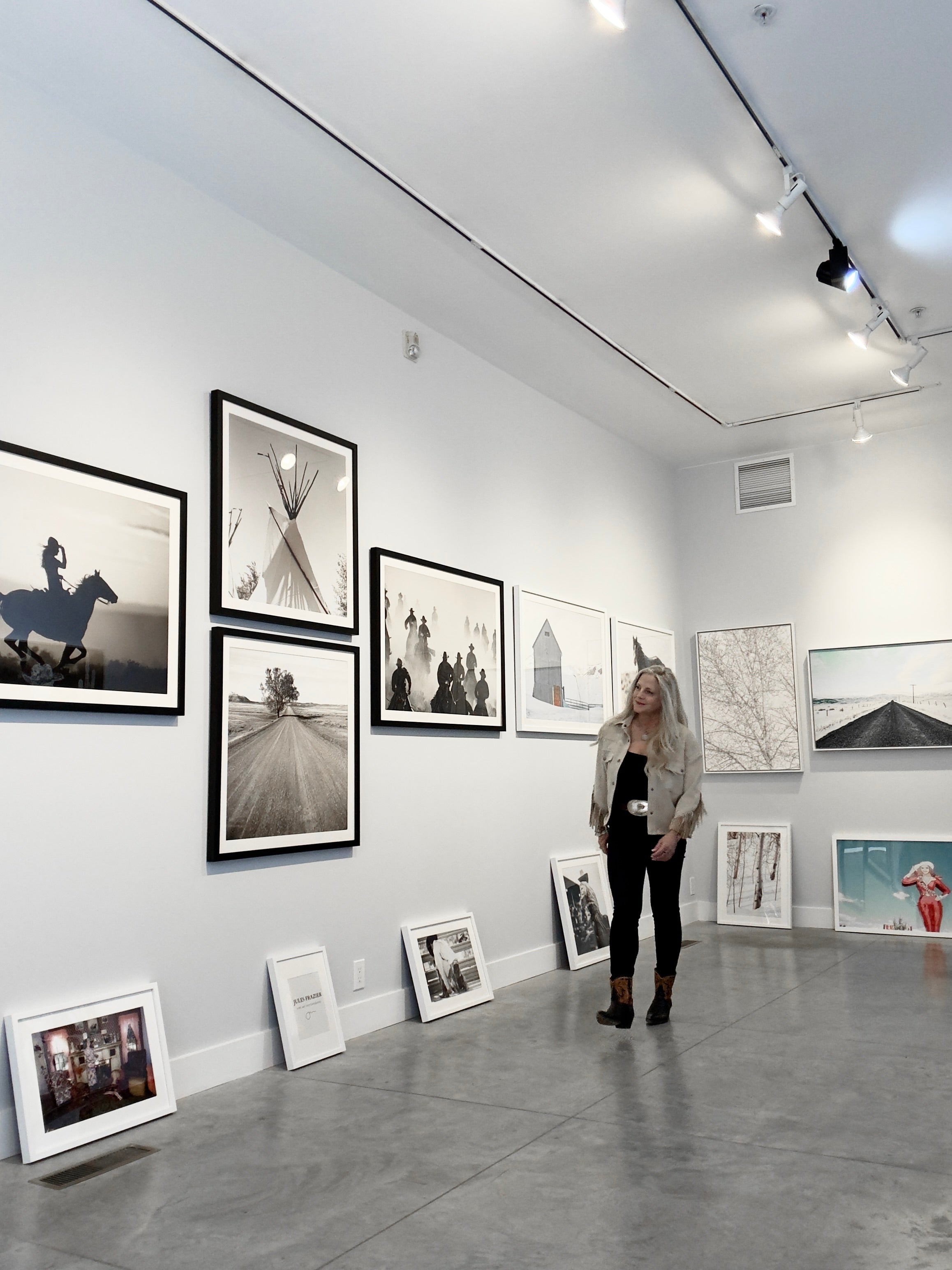 Woman standing in an art gallery with framed photographs on the walls.