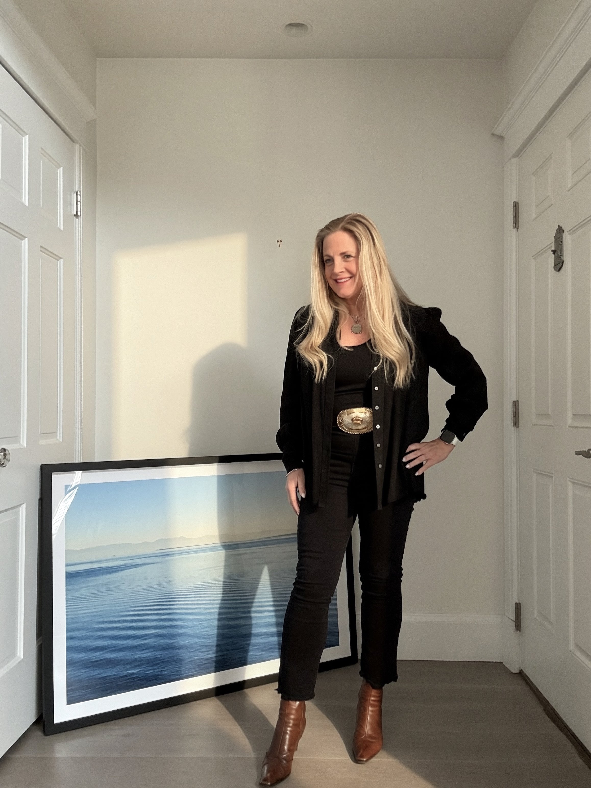 Woman standing in a room with a large framed picture of water on the floor.