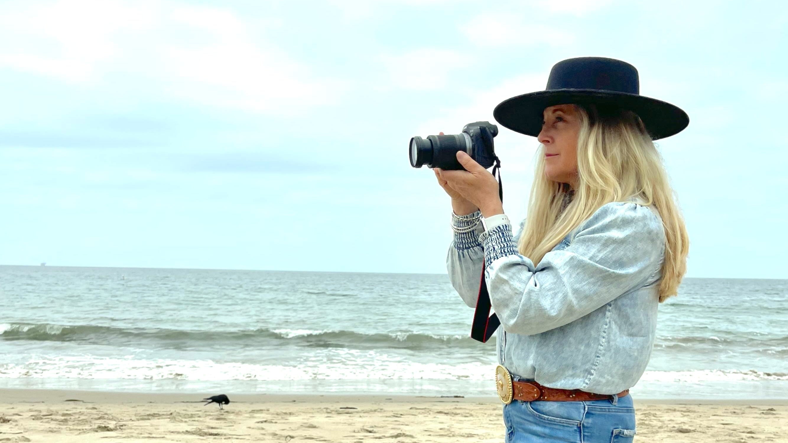 Woman taking a photo on a beach with a camera
