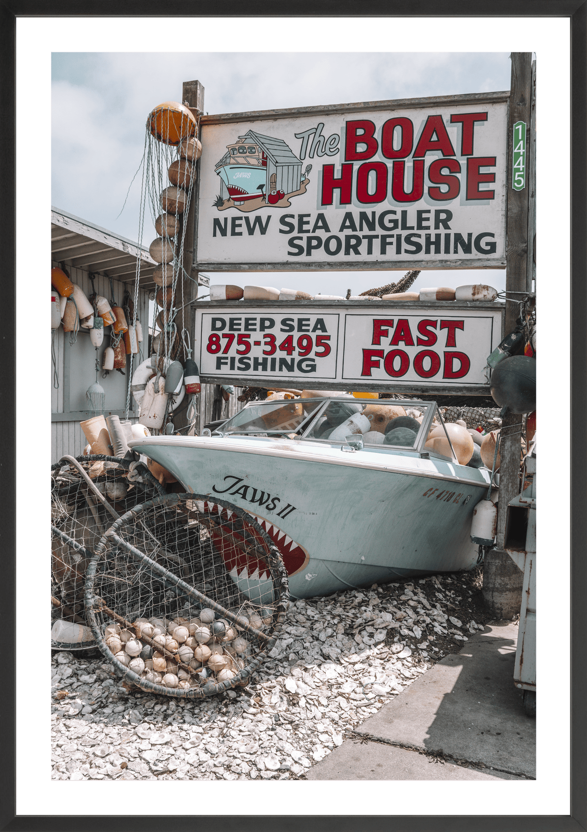 Coastal classic brimming with vintage memorabilia, Boat House, modern fine art print with retro seaside charm. Black frame.