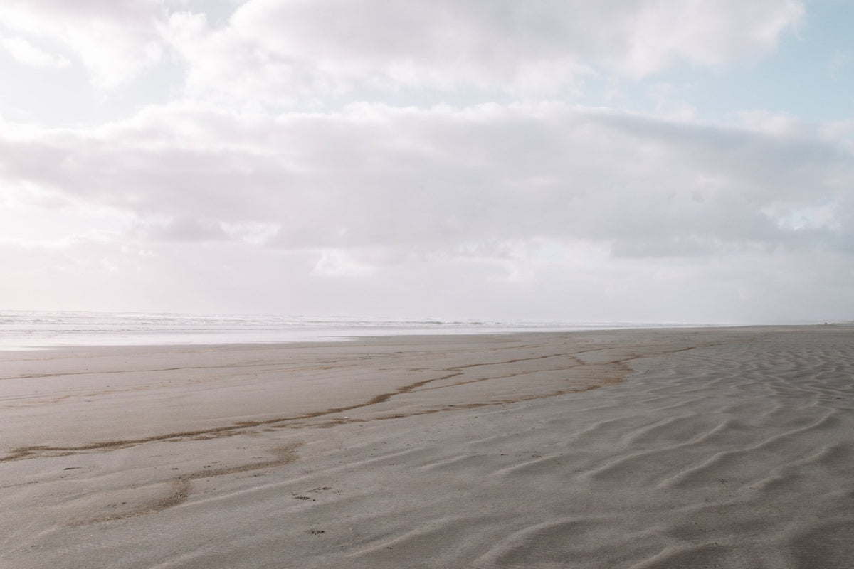 Wet sand on a beach with a cloudy sky