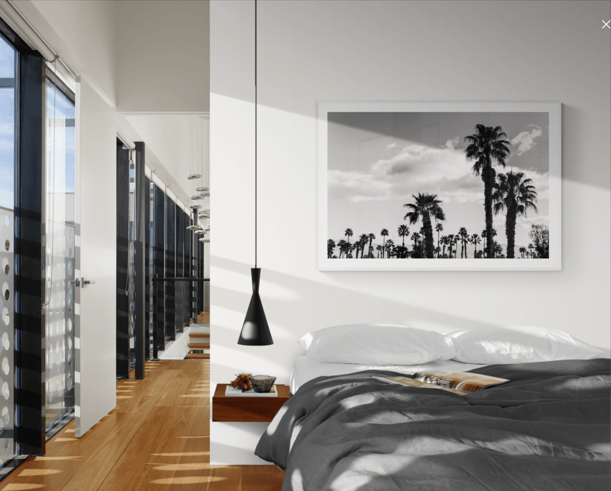 Morning Palm Desert fine art print in a white frame above a bed, by Jules Frazier