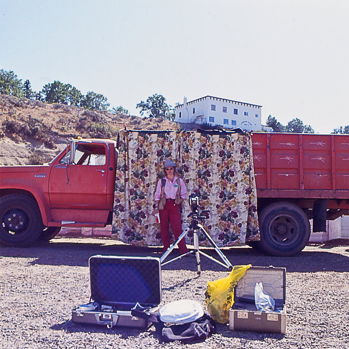 Red truck with a trailer carrying a large floral arrangement, with a person standing next to it.
