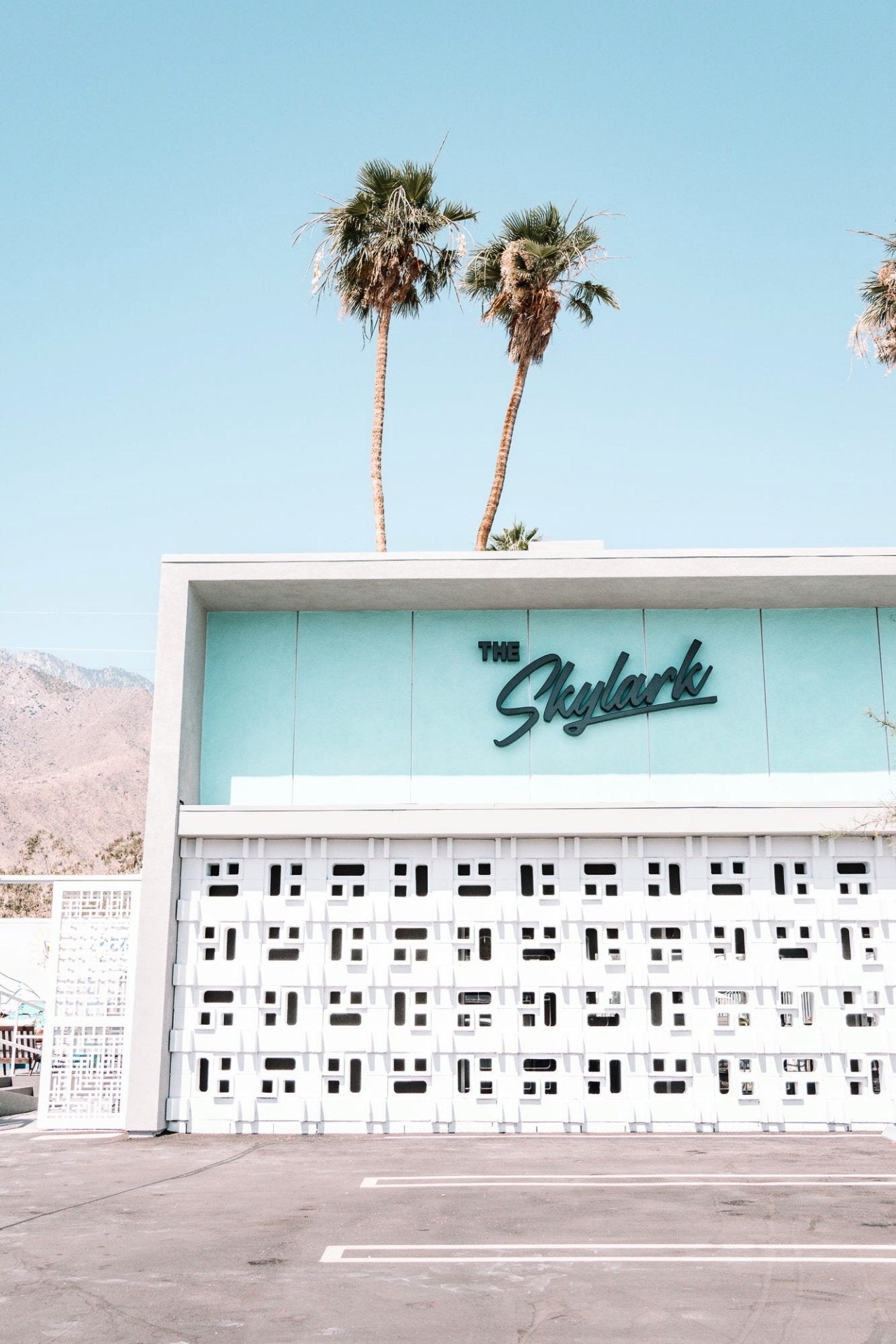 Building with The Skylark motel sign and palm trees against a blue sky