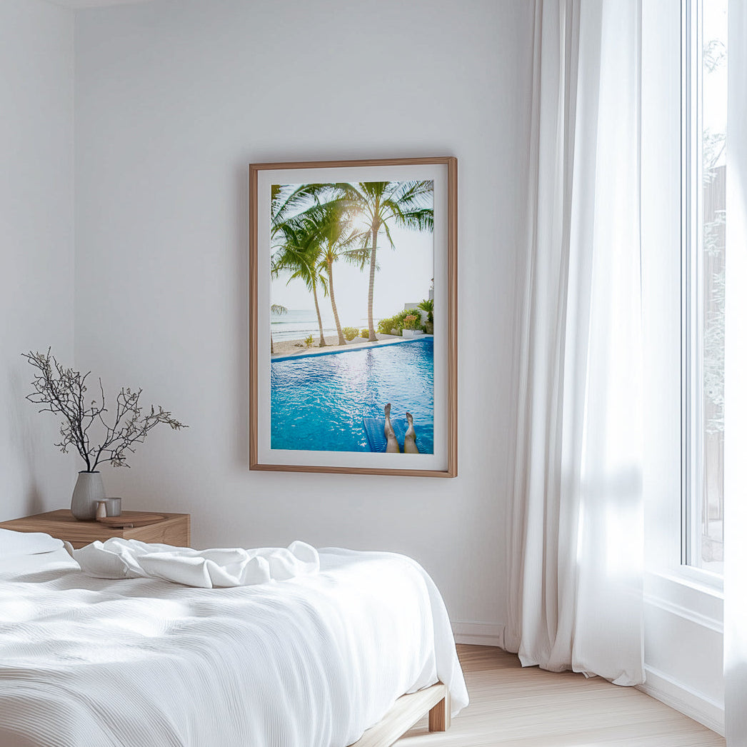 Modern bedroom with a framed picture of a pool and palm trees on the wall.