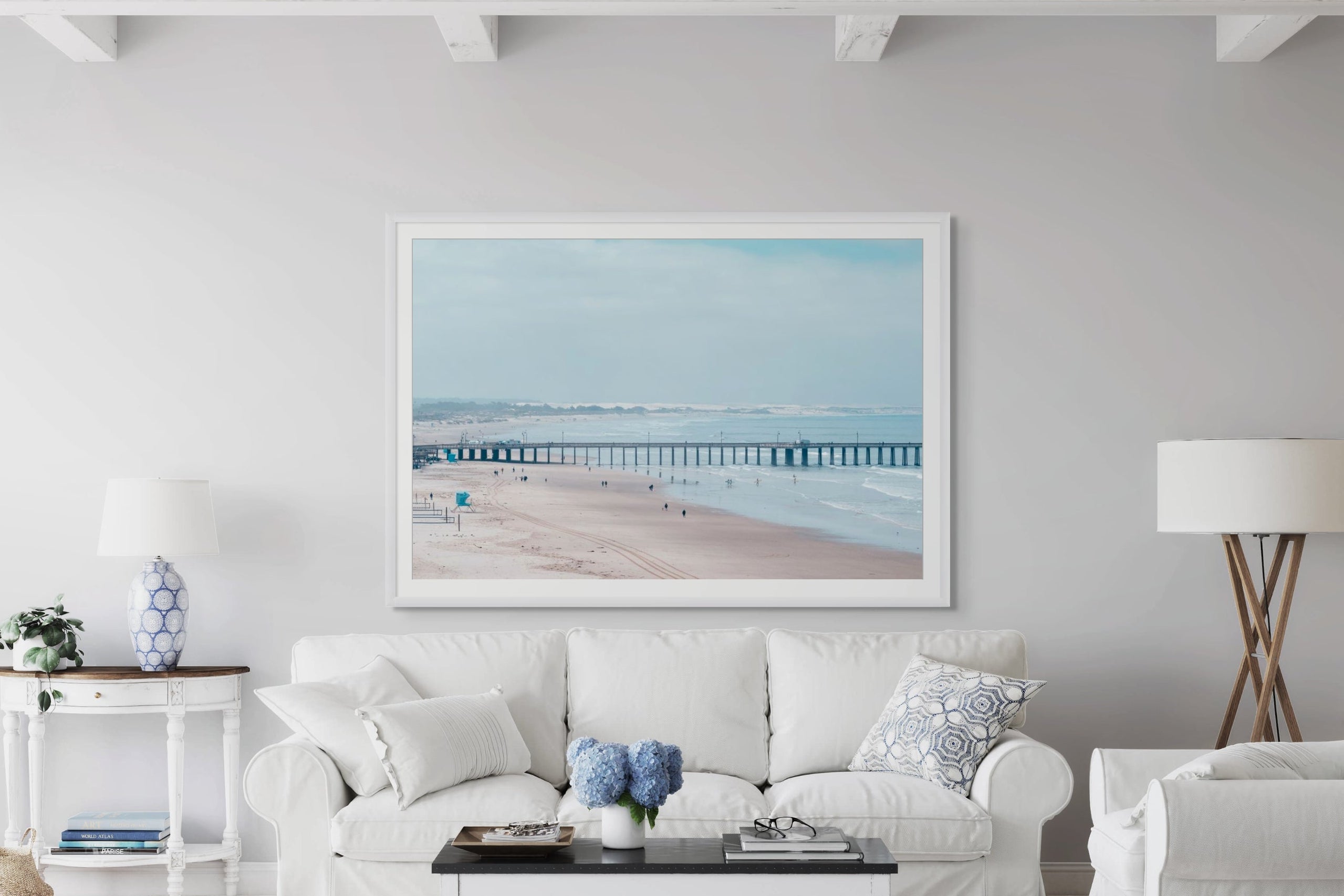 Living room with white furniture and a large framed picture of a beach.