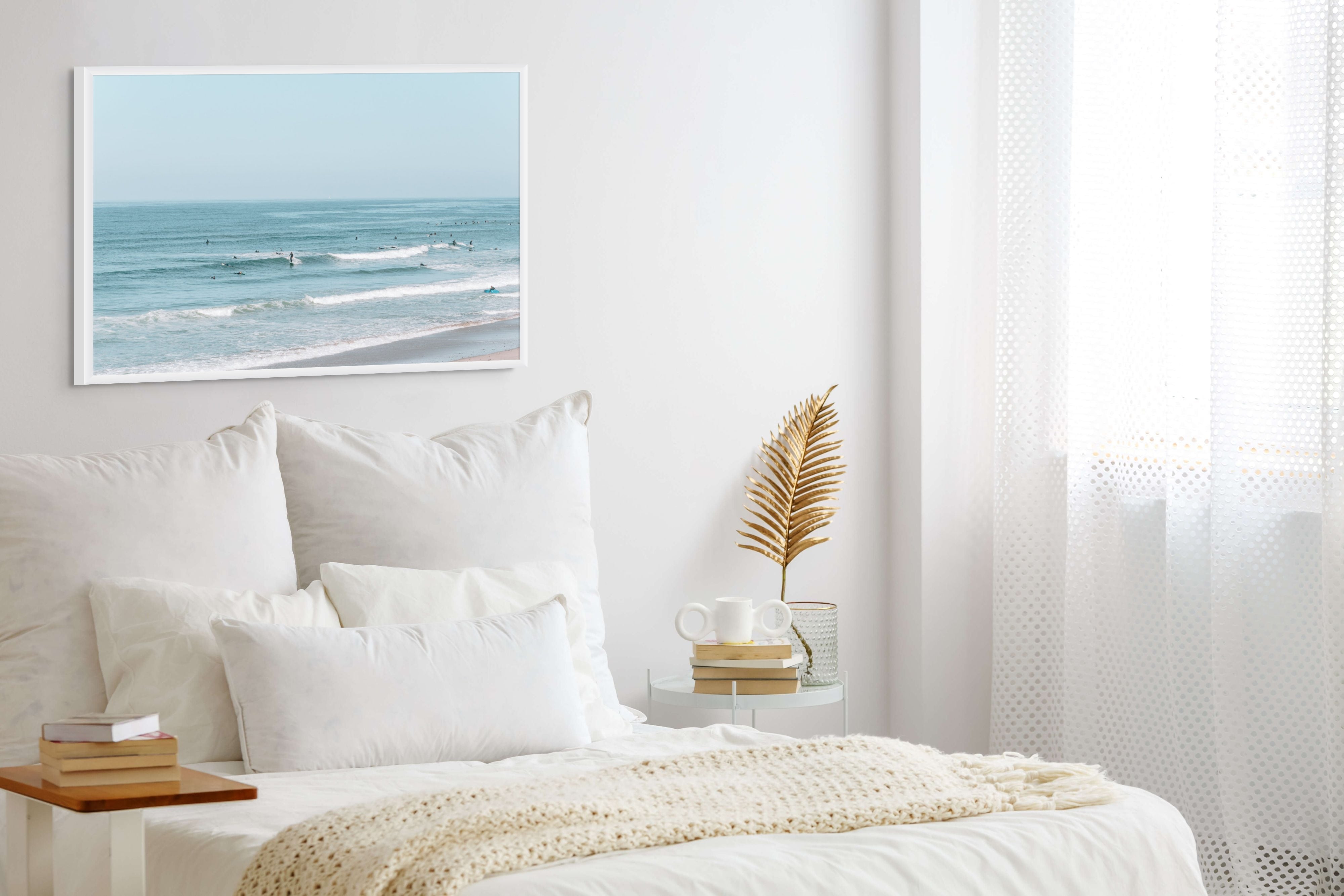 Bedroom with a large bed, white bedding, and a framed picture of a beach on the wall.